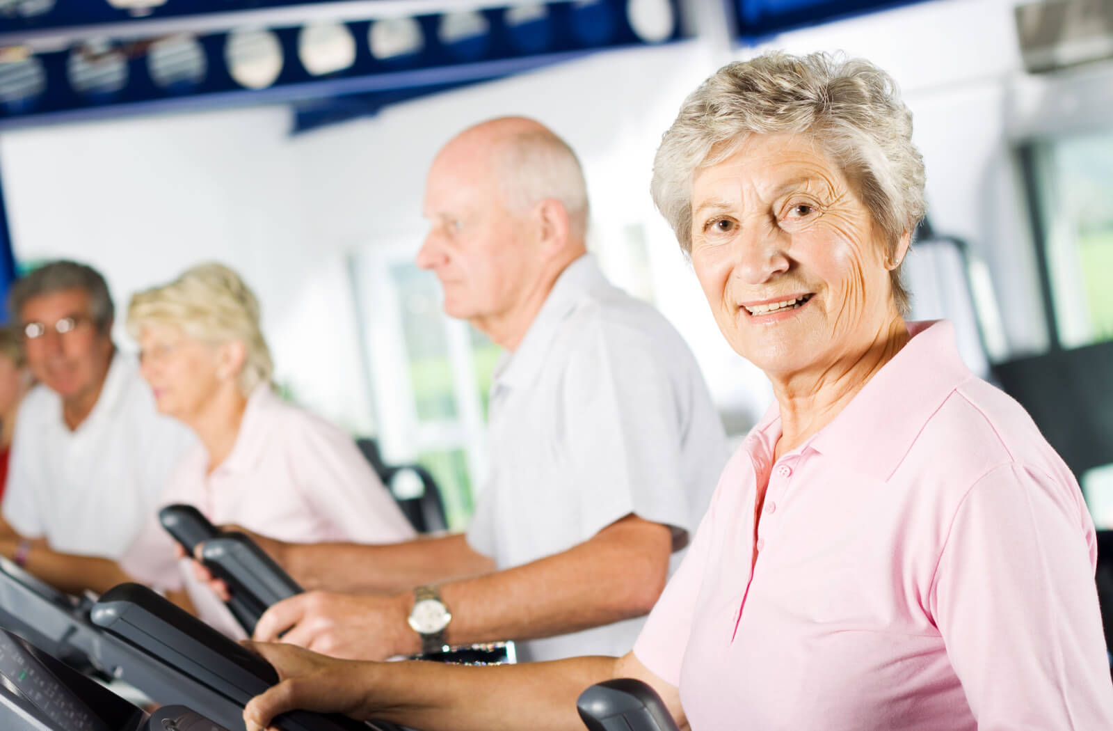 A group of older adults using treadmills indoors during a fitness class to boost cardio.