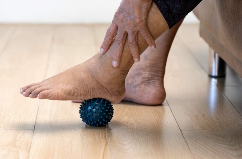 An older adult woman doing a foot massage using a rubber ball